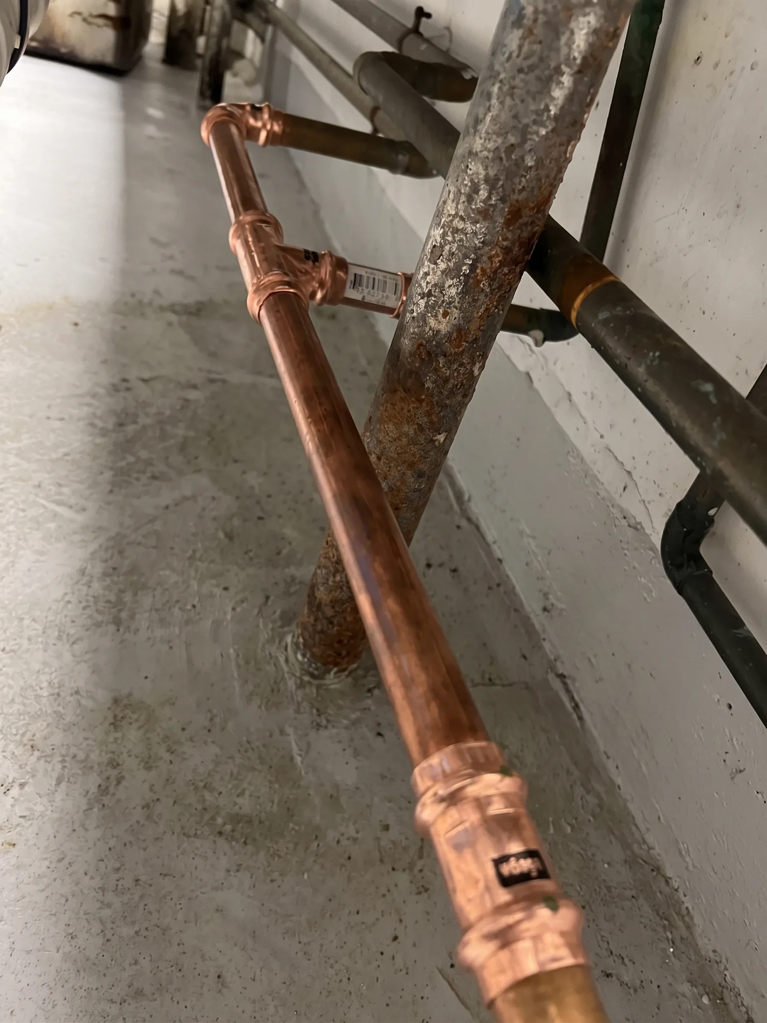 New copper water line with press fittings running alongside the corroded galvanized pipe it replaced