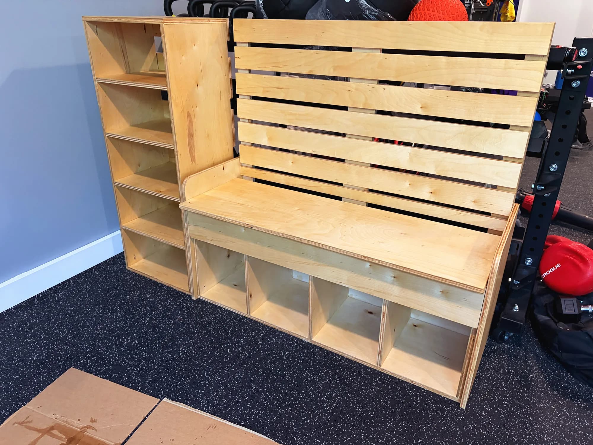 Custom plywood bench with slatted back and four cubbies underneath, beside a matching shelf unit
