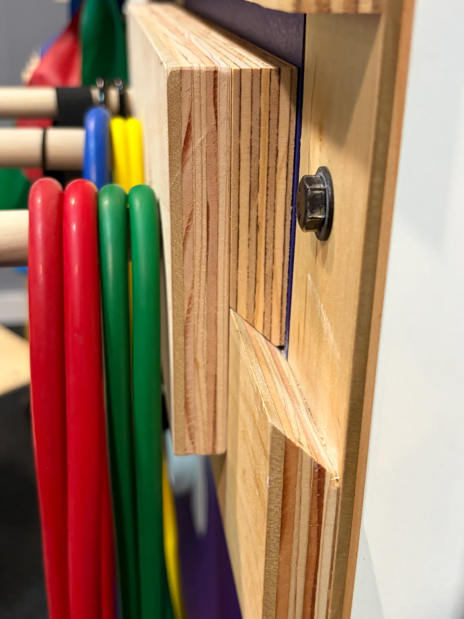 Close-up of the bevelled plywood cleat and through-bolt holding the band wall to the wall