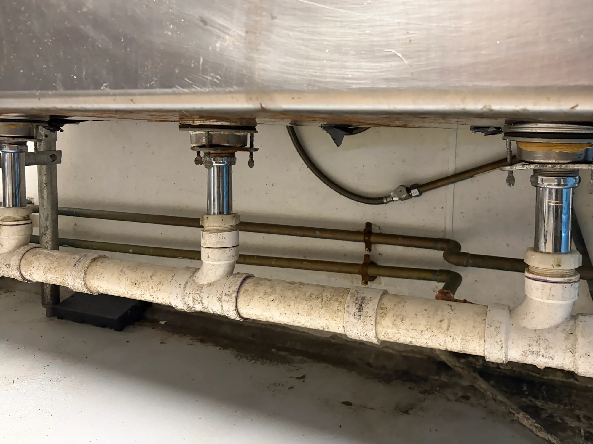 The same sink after replacement, with new chrome tailpieces and sealed connections